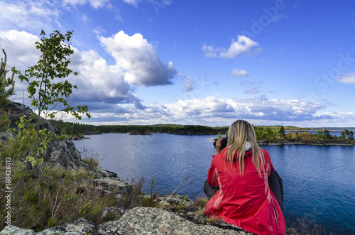 On the shore of Ladoga Lake, a girl in a red jacket with a camera
