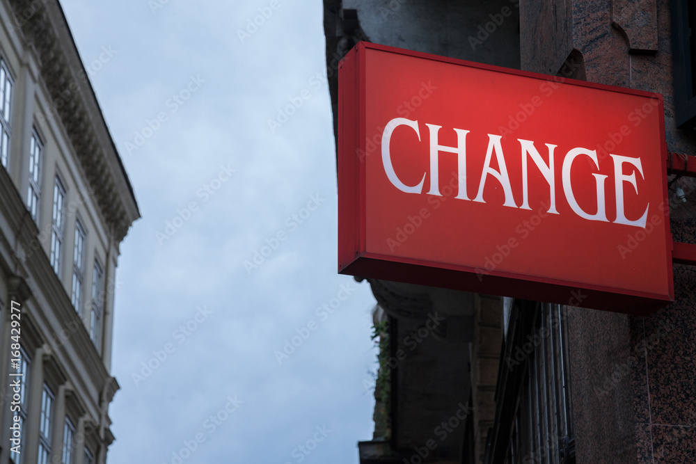 Fototapeta premium Red sign with the word change written, with buildings in the background, while night is approaching.