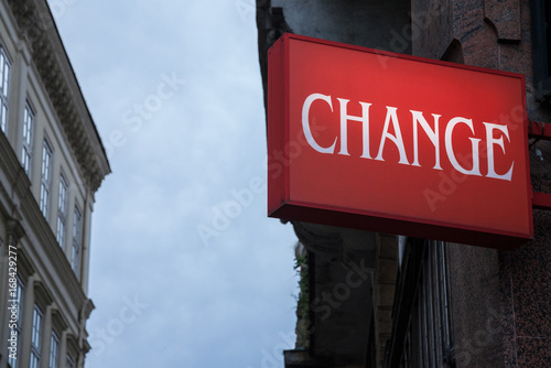 Red sign with the word change written, with buildings in the background, while night is approaching. photo