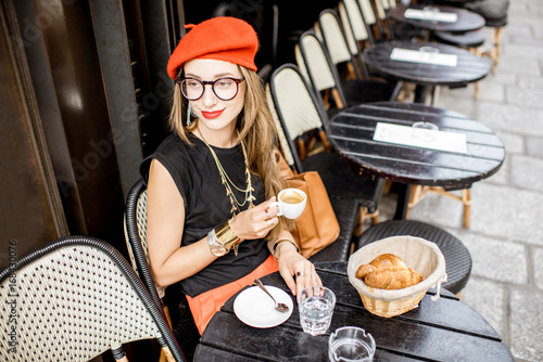 Canvas Print Young stylish woman in red beret having a french breakfast with coffee and crois