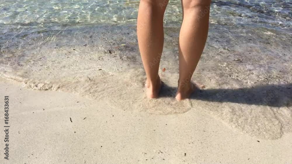 Primo piano ragazza con piedi in acqua al mare con acqua cristallina Primo piano ragazza con piedi in acqua al mare con acqua cristallina