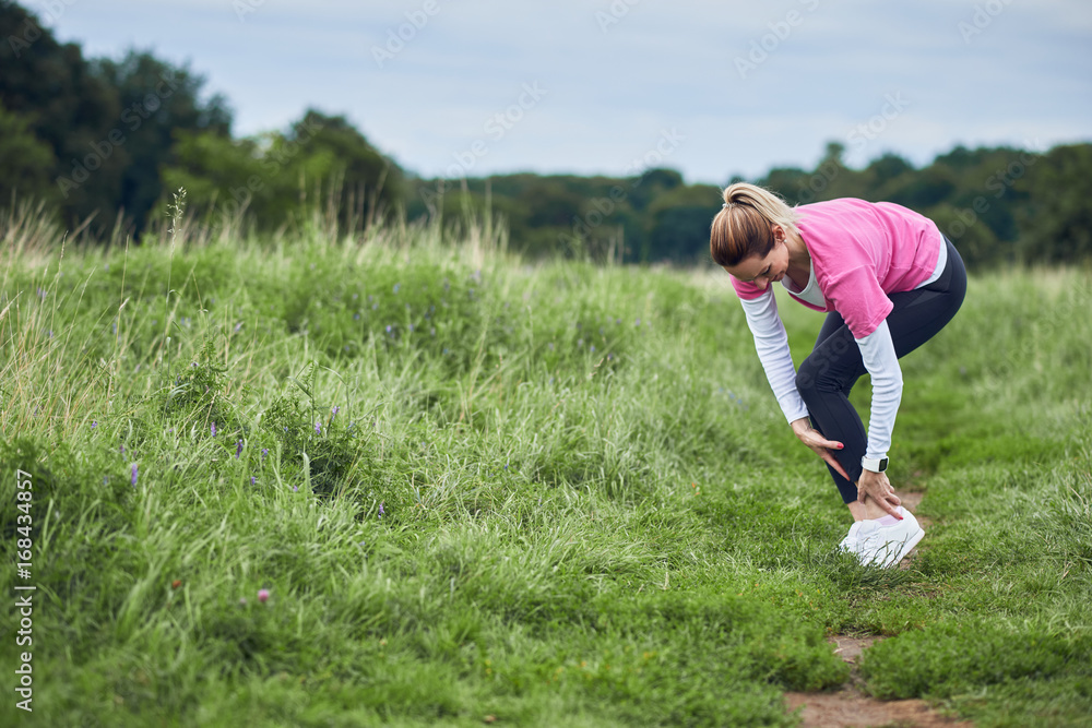 Eine Frau ist beim Training umgeknickt und fasst sich an das Sprunggelenk Eine Frau ist beim Training umgeknickt und fasst sich an das Sprunggelenk