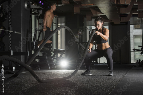 Tablou canvas Strong athlete woman wearing a black sports bra and long tights in a dark gym wi