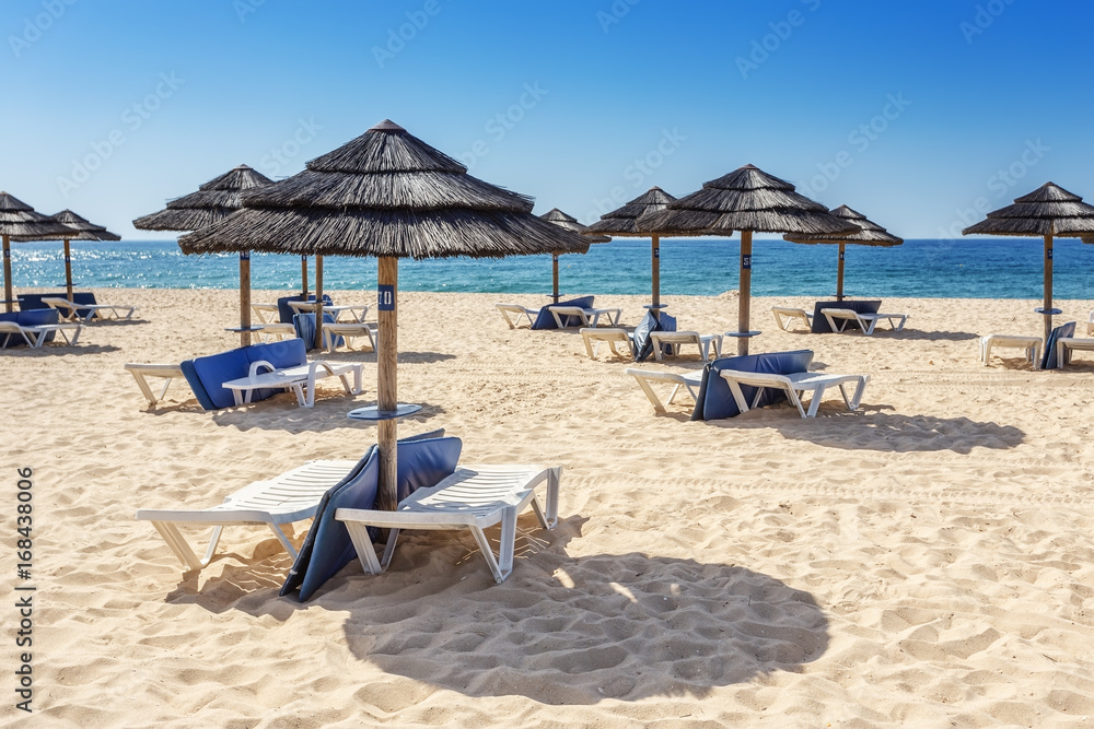 Umbrellas and sunbeds on the southern beach of the Algarve. Portugal. Umbrellas and sunbeds on the southern beach of the Algarve. Portugal.