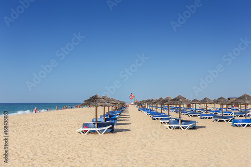 Summer morning on the beach of Tavira Island. Empty beds in sand.