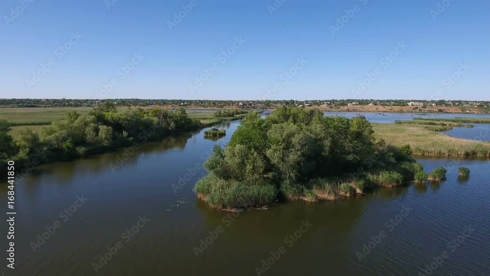 Impressive bird`s eye view of the Dnipro river with its wide inflows, wild river banks, trees, bushes, lawns, wetland, and lakes on a sunny day in summer. The skyscape is blue and nice. Impressive bird`s eye view of the Dnipro river with its wide inflows, wild river banks, trees, bushes, lawns, wetland, and lakes on a sunny day in summer. The skyscape is blue and nice.
