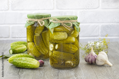 Pickled cucumbers in glass jar on a gray wooden table.