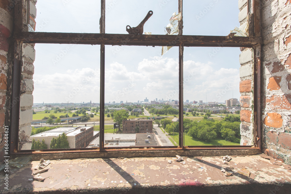 Looking out the window of an abandoned window towards the skyline of Detroit
