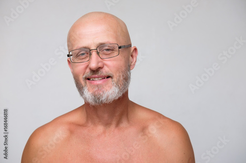Fototapeta portrait of adult bearded bold skinhead grizzled man in eyeglasses on white