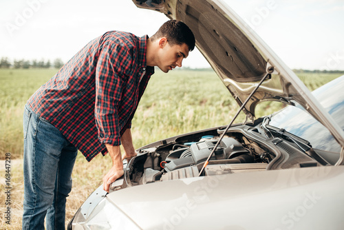 Tired man tries to repair a broken car © Nomad_Soul