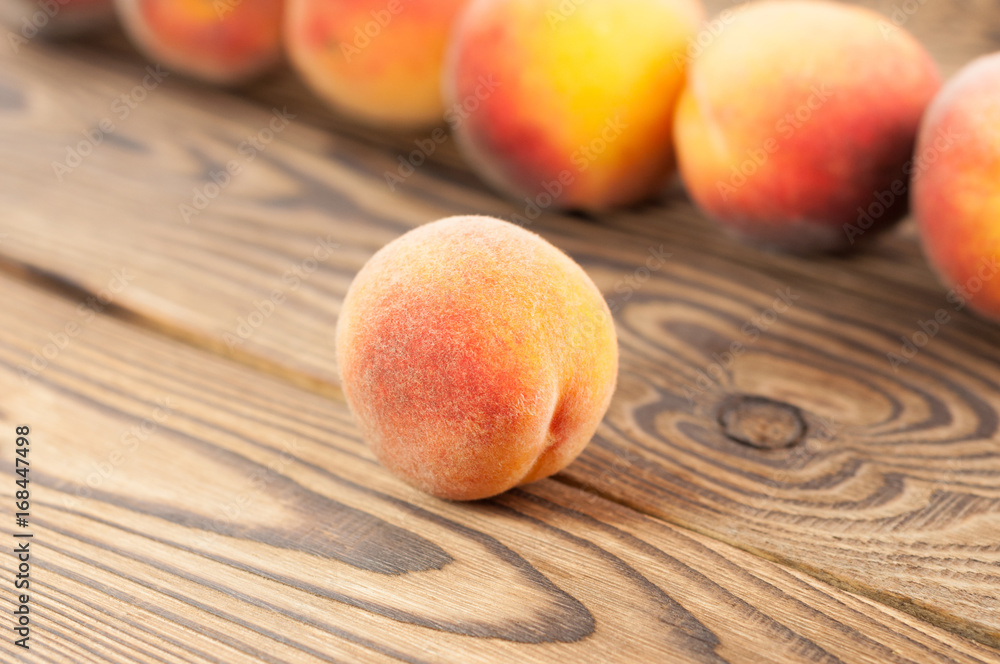 Row of fresh whole ripe peaches and one peach separately on old rustic wooden planks Row of fresh whole ripe peaches and one peach separately on old rustic wooden planks