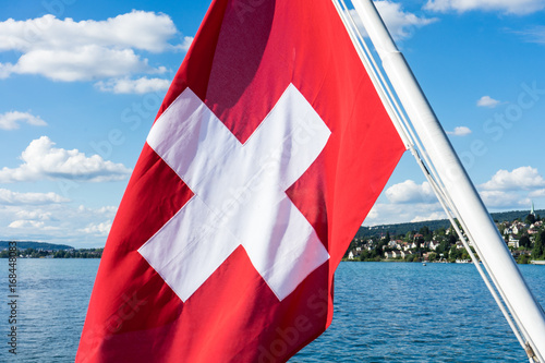 swiss national flag on lake with water and blue sky photo