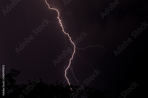 Lighting in the night striking at the ground with sheer force in the storm and clouds in the sky