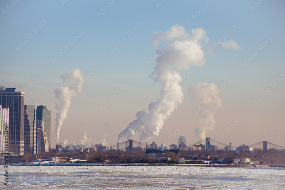 Climate change. Tip of Lower Manhattan, Brooklyn Bridge, Manhattan Bridge.  Industrial Steam smoke rising. 