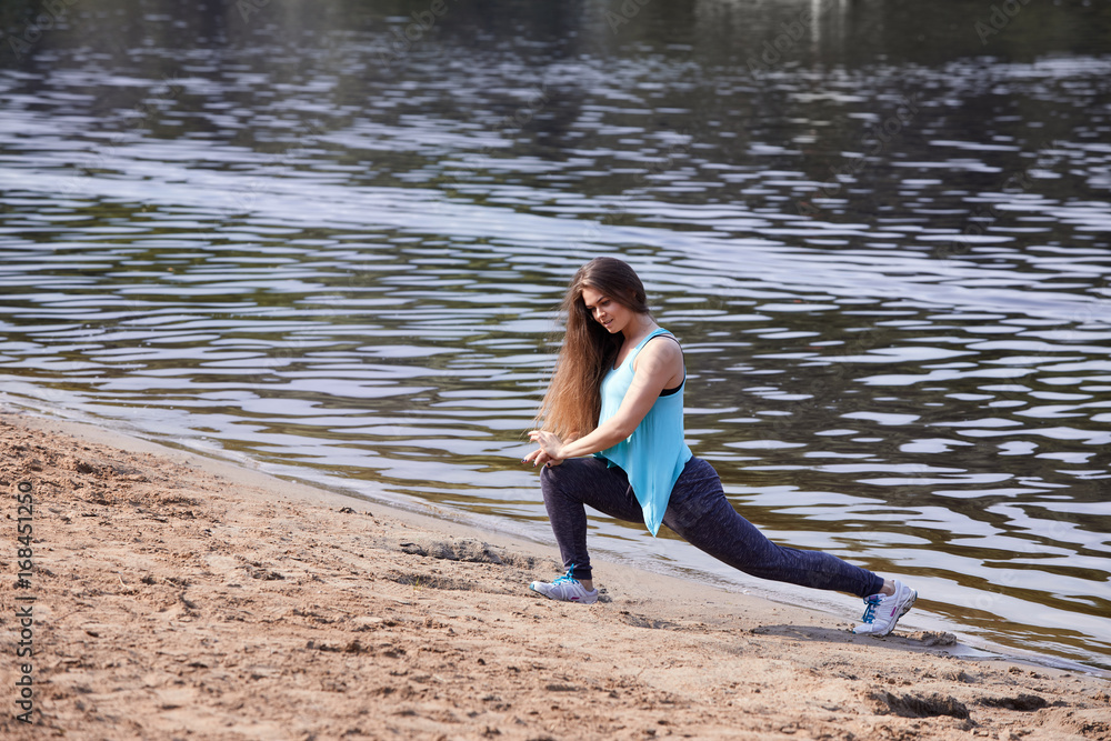 A girl with long hair trains on the sand near the water. A girl with long hair trains on the sand near the water.
