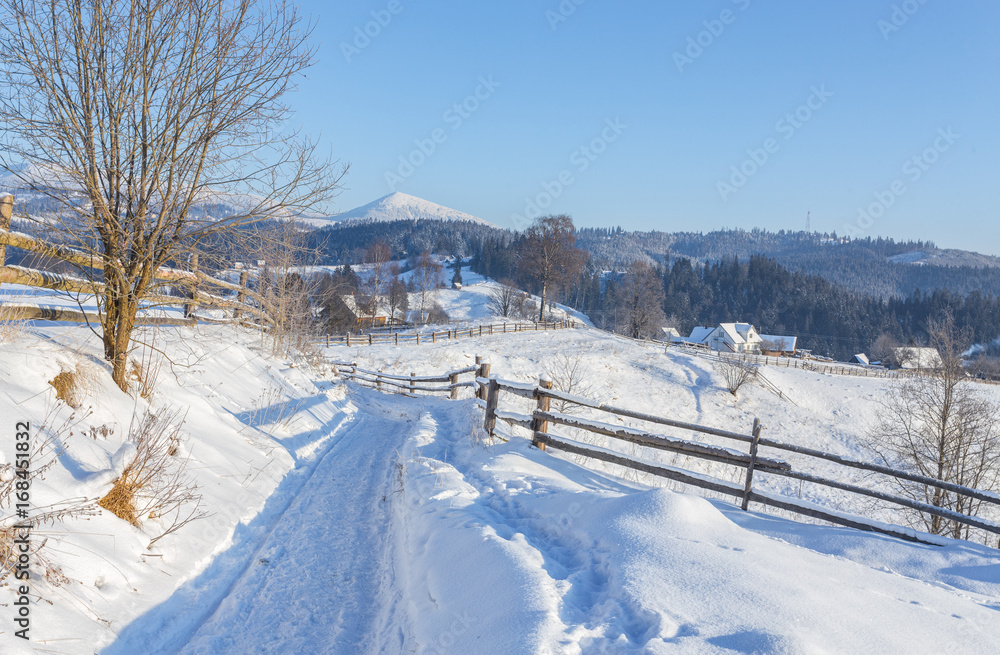 Winter country landscape with timber fence and snowy road