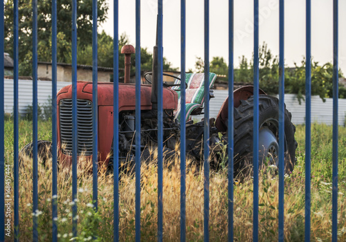 Red old tractor behind a blue fence