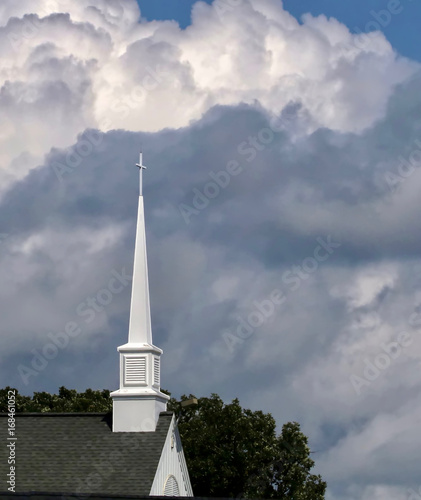 Foto A white church steeple against blue puffy clouds