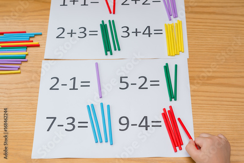 Fotografi kid learning simple subtraction and addition by counting numbers of sticks
