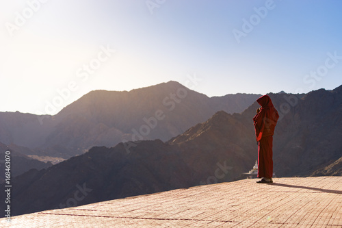 Fototapeta Lama (Tibetan monk) gazing the mountain range and blue sky in Leh Ladakh