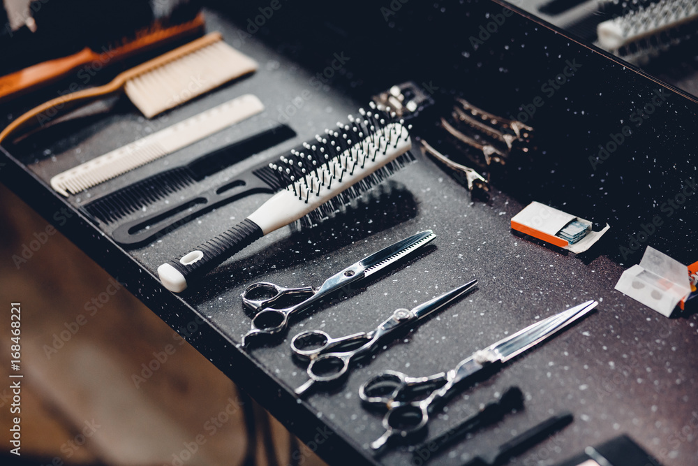 Fototapeta premium Set of tools for barbershop of male hairdresser on dark background: scissors, nozzle for hair clipper, calculation, teeth. Concept abstract background for business.