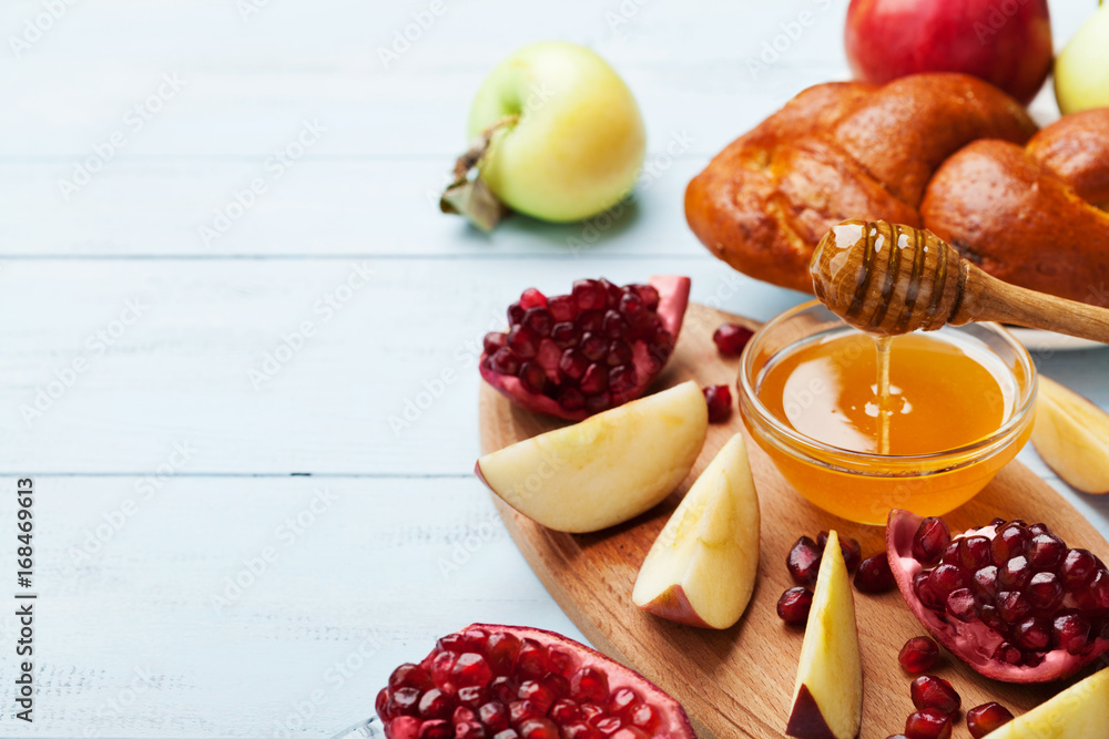 Honey, apple slices, pomegranate and hala serve on wooden kitchen board. Table set with traditional food for Jewish New Year Holiday, Rosh Hashana. Copy space for text. - obrazy, fototapety, plakaty 
