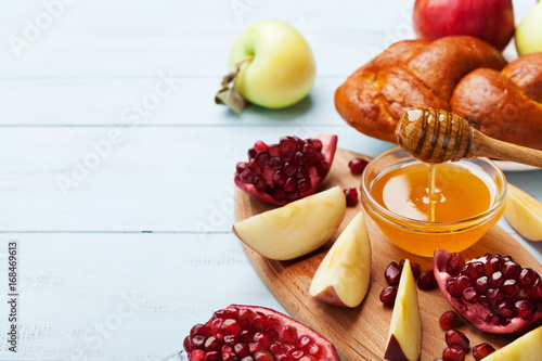 Honey, apple slices, pomegranate and hala serve on wooden kitchen board. Table set with traditional food for Jewish New Year Holiday, Rosh Hashana. Copy space for text.