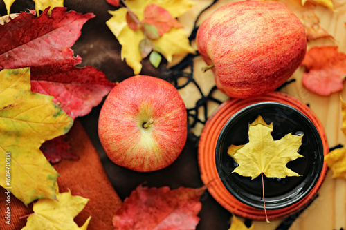 Autumn tea. Cup of tea with maple autumn leaves, Apples and woolen rug on a wooden table. autumn mood. 