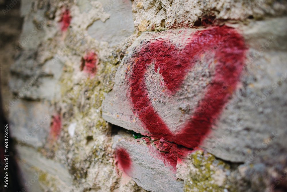 Close up background graffiti silhouette of red heart on an old relief stone wall