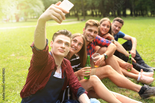 Young friends taking selfie during barbecue picnic.