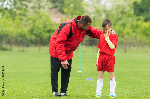 Kids soccer football - coach comfort little soccer player after a missed goal