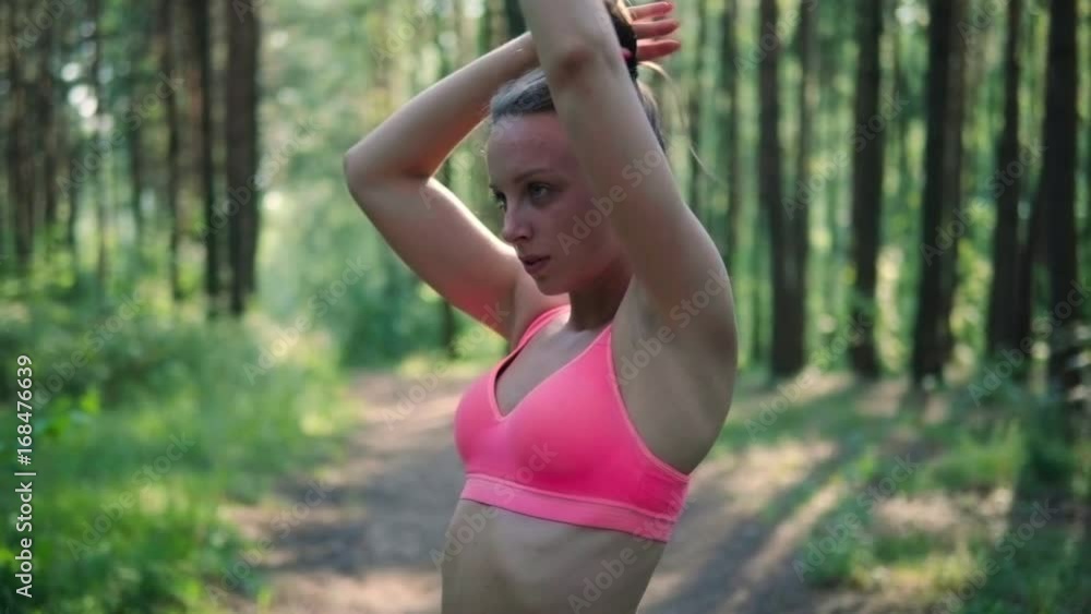 Young athletic woman collects hair in a tail before jogging in the forest Young athletic woman collects hair in a tail before jogging in the forest