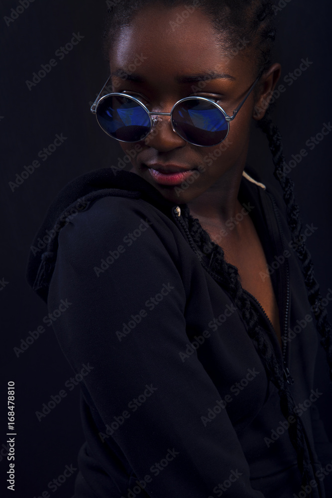 Cool young woman with dark skin wearing round sunglasses