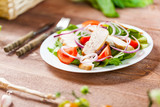 Fresh salad with chicken, tomato and greens on wooden background top view. Healthy food.
