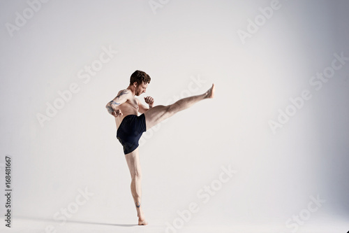 Wallpaper Mural Confident athletic MMA Fighter or kickboxer wearing black shorts and gloves boxing in studio, kicking air in front of him, preparing for competiton. Sports, healthy lifestyle and martial arts concept Torontodigital.ca