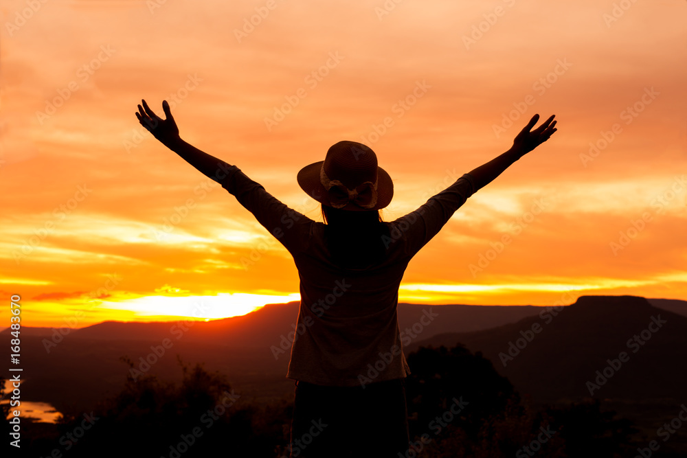 silhouette woman stands on mountain top at sunset time,Freedom happy woman enjoying nature sunset