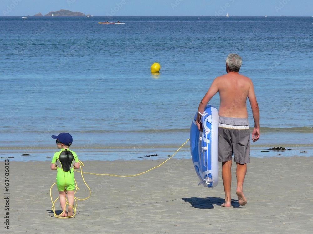 Εκτύπωση καμβά Un grand-père avec son petit fils partent se baigner avec un bateau gonflable