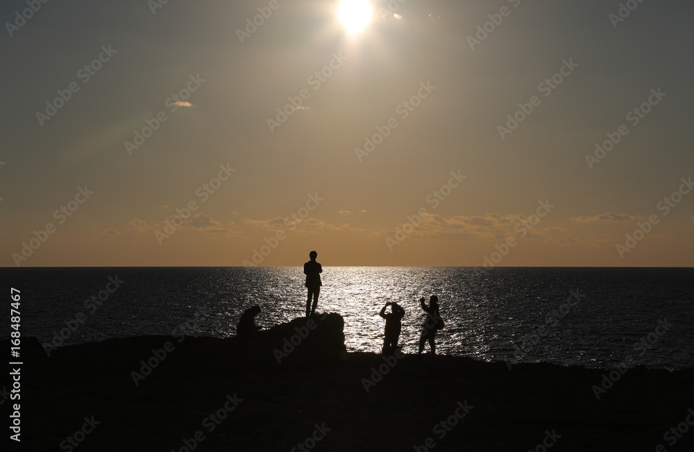 Four people watching sunset on beacch