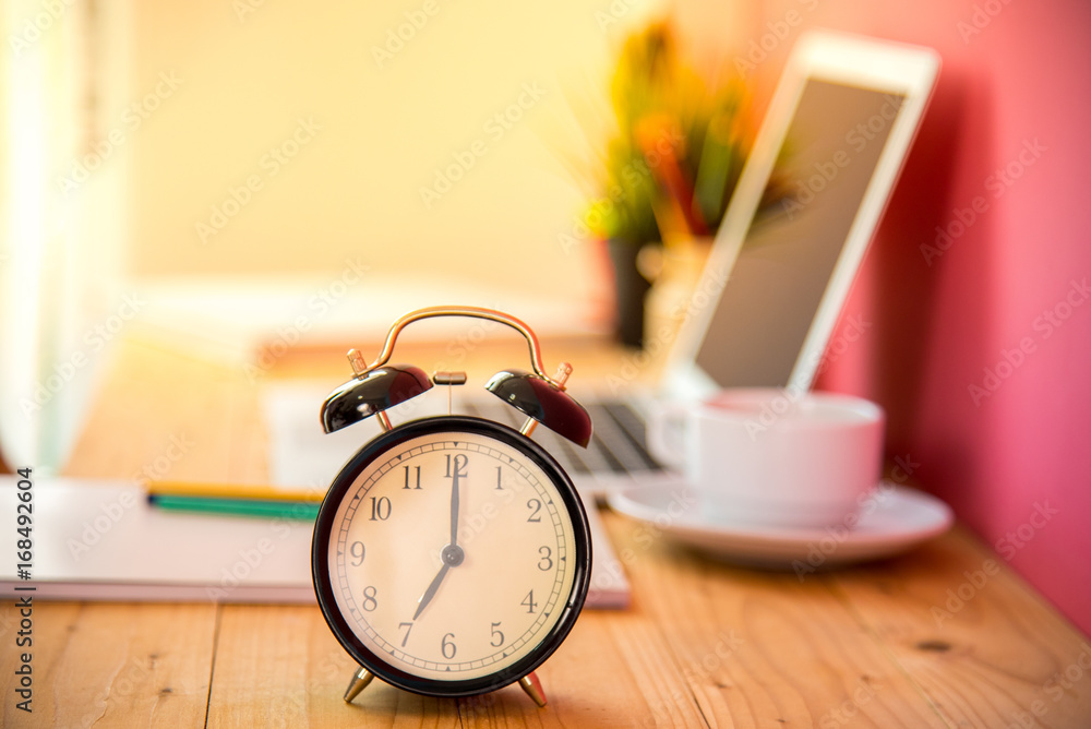 Alarm at 7 o'clock with blur laptop and cup of tea on table background.  Good morning and start of new work day. Business concept. Photos | Adobe  Stock