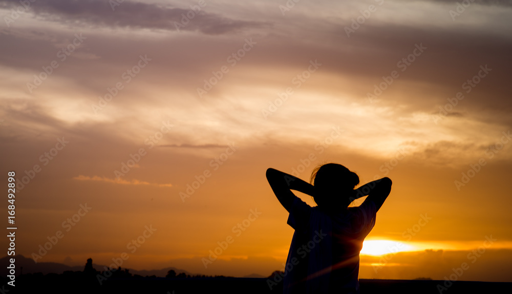 Silhouette of strong confident woman open arms with mountain sunset background. Happy girl, sunset and golden sky at twilight.