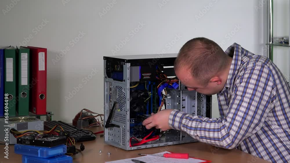 Man Installing Computer Young repairer man installing hard drive into desktop pc case at ...