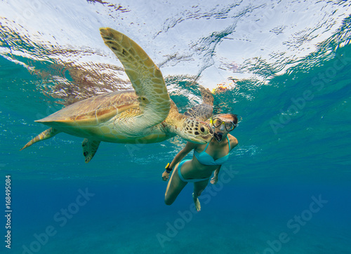 Snorkeling woman with hawksbill turtle, underwater photography.