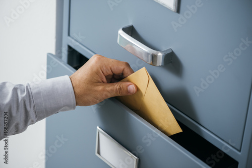 Businessman putting an envelope into a drawer