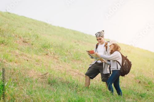 Couple of backpacking hikers going to mountain top and navigating by map. Backpackers or Hikers travel concept. Selective focus.