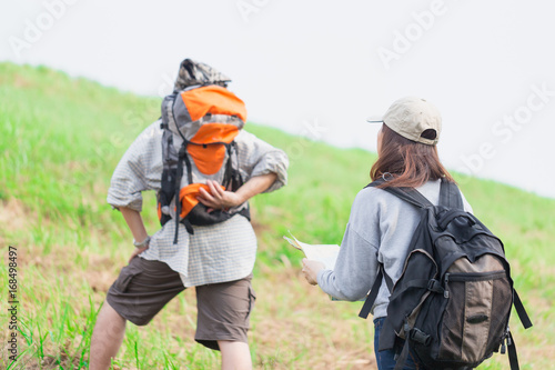 Couple of backpacking hikers going to mountain top and navigating by map paper. Backpackers or Hikers travel concept. Selective focus.