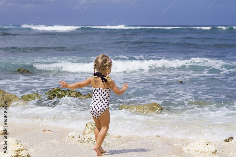 Child on the ocean background / Little girl is running to the ocean Child on the ocean background / Little girl is running to the ocean