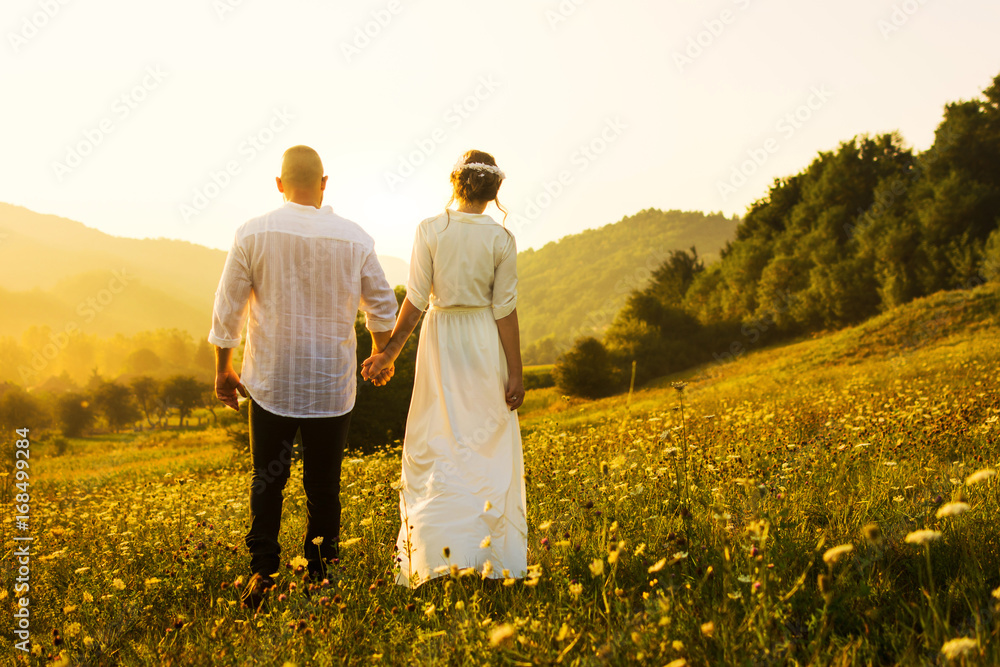 Couple walking on the field with sunset view