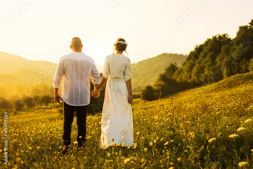 Couple walking on the field with sunset view