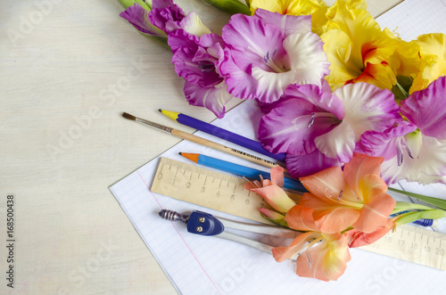 Bouquet of gladiolus flowers and school supplies.