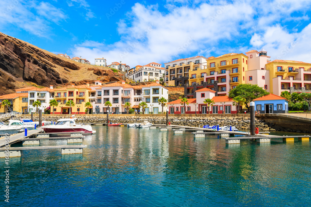 Boats in marina with colourful houses near Canical town on coast of Madeira island, Portugal